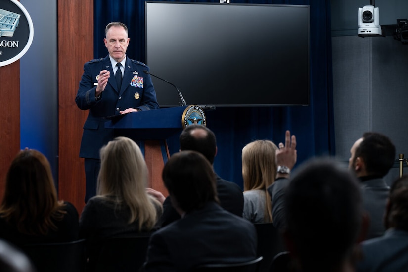 A man in uniform stands at a lectern.