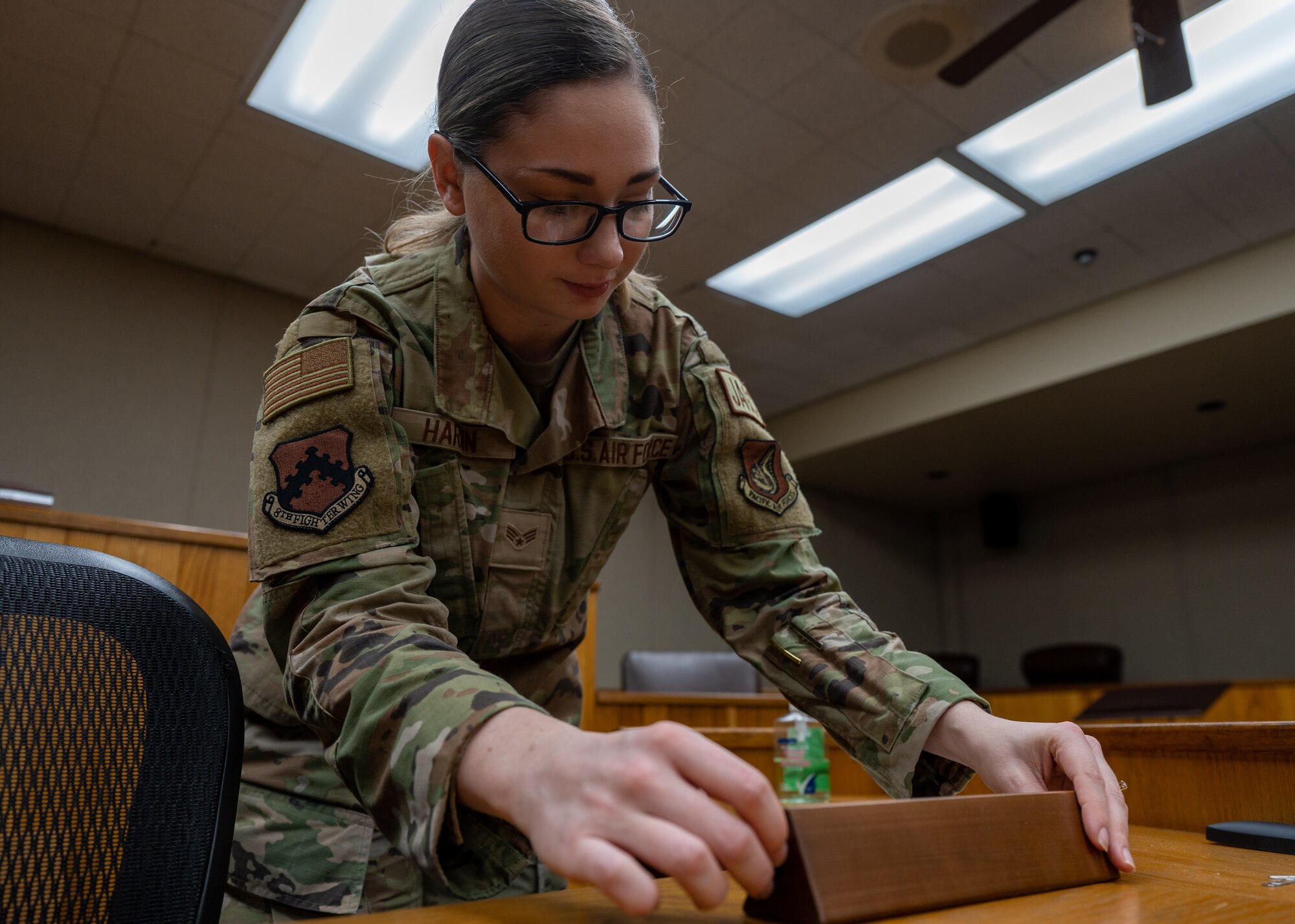Senior Airman Erin Hardin prepares a courtroom before use.