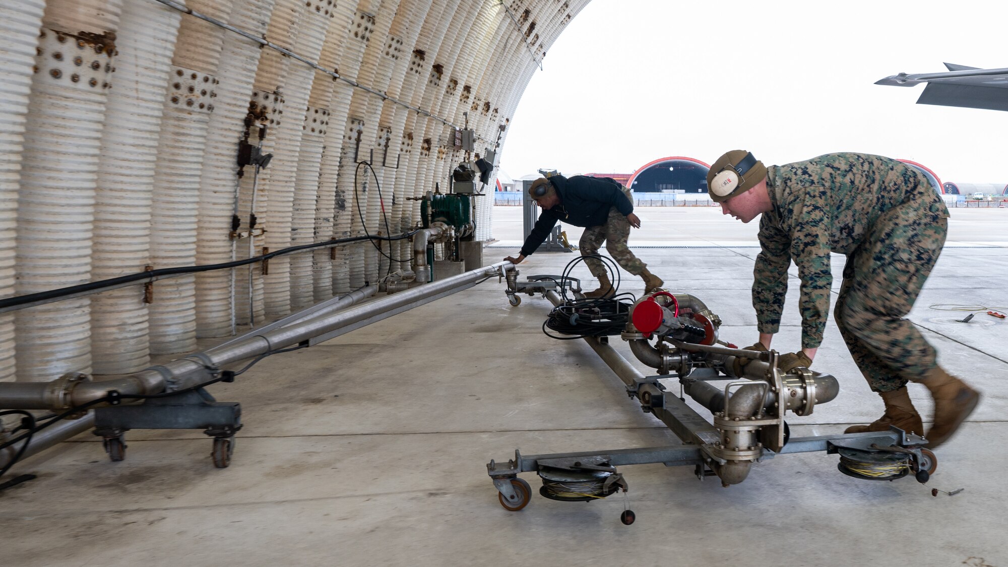 U.S. Air Force Senior Airman Andre Franklin, left, and U.S. Marine Lance Cpl. Brandon Braly repare equipment prior to refueling an F-35A Lightning II.