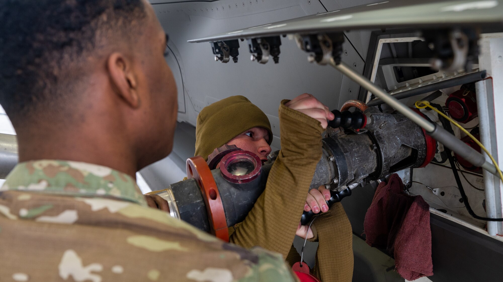 U.S. Marine Lance Cpl. Nathan Jones, right, and U.S. Air Force Senior Airman Andre Franklin fasten a fuel hose to an F-35A Lightning II.