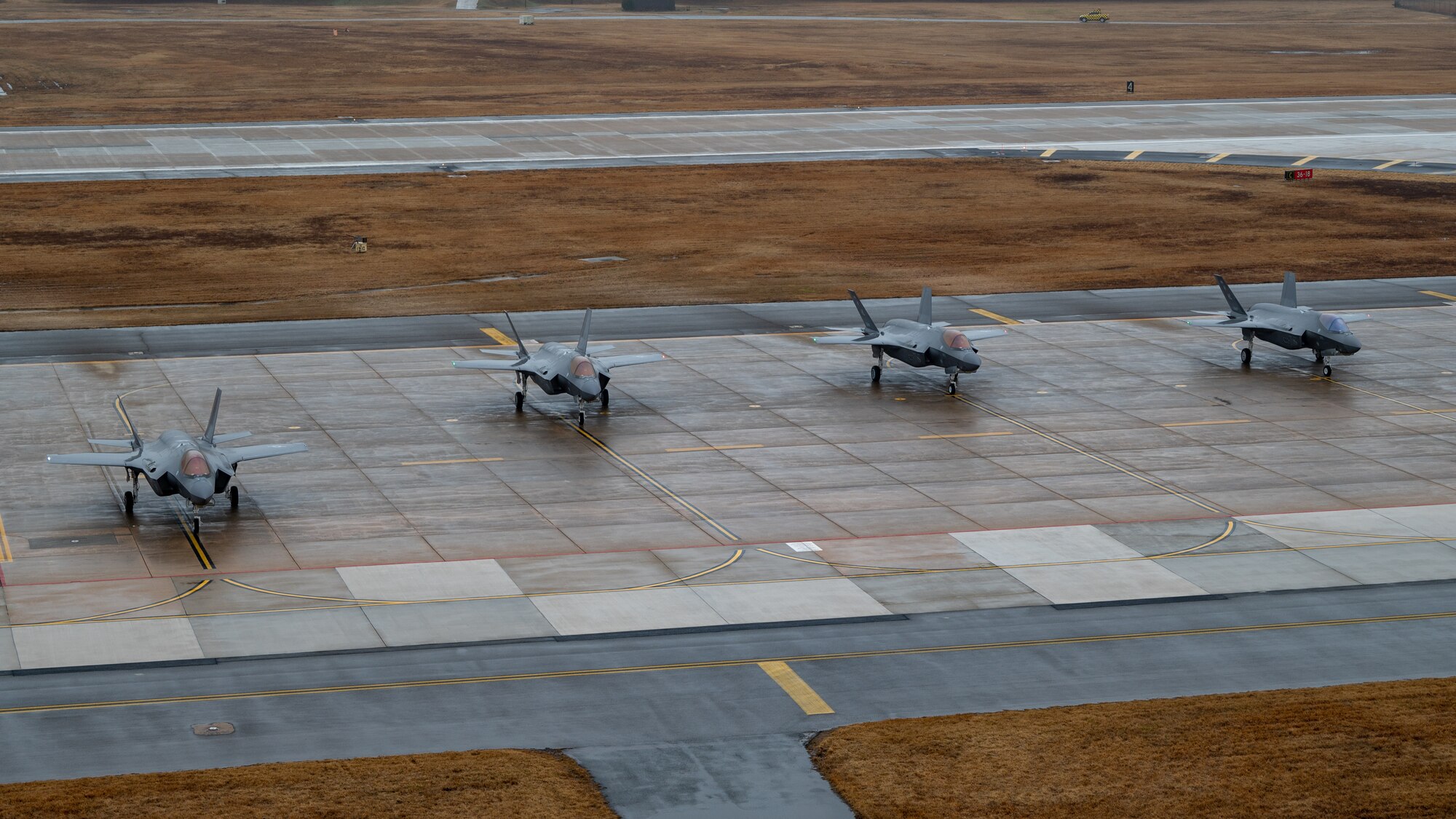 Four F-35A Lightning IIs taxi on the runway before take-off.