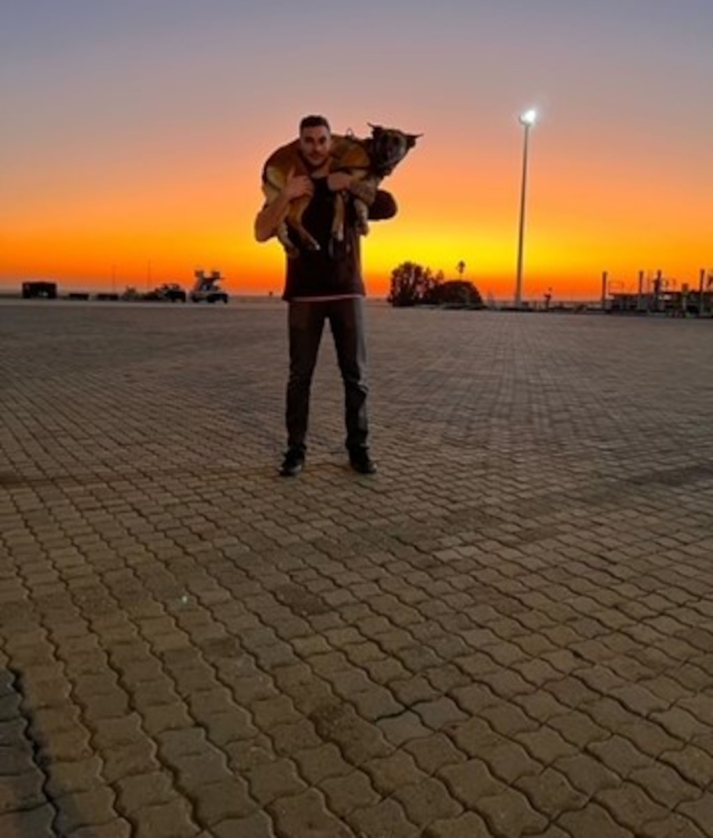 handler and his dog in a large city square at sunrise.