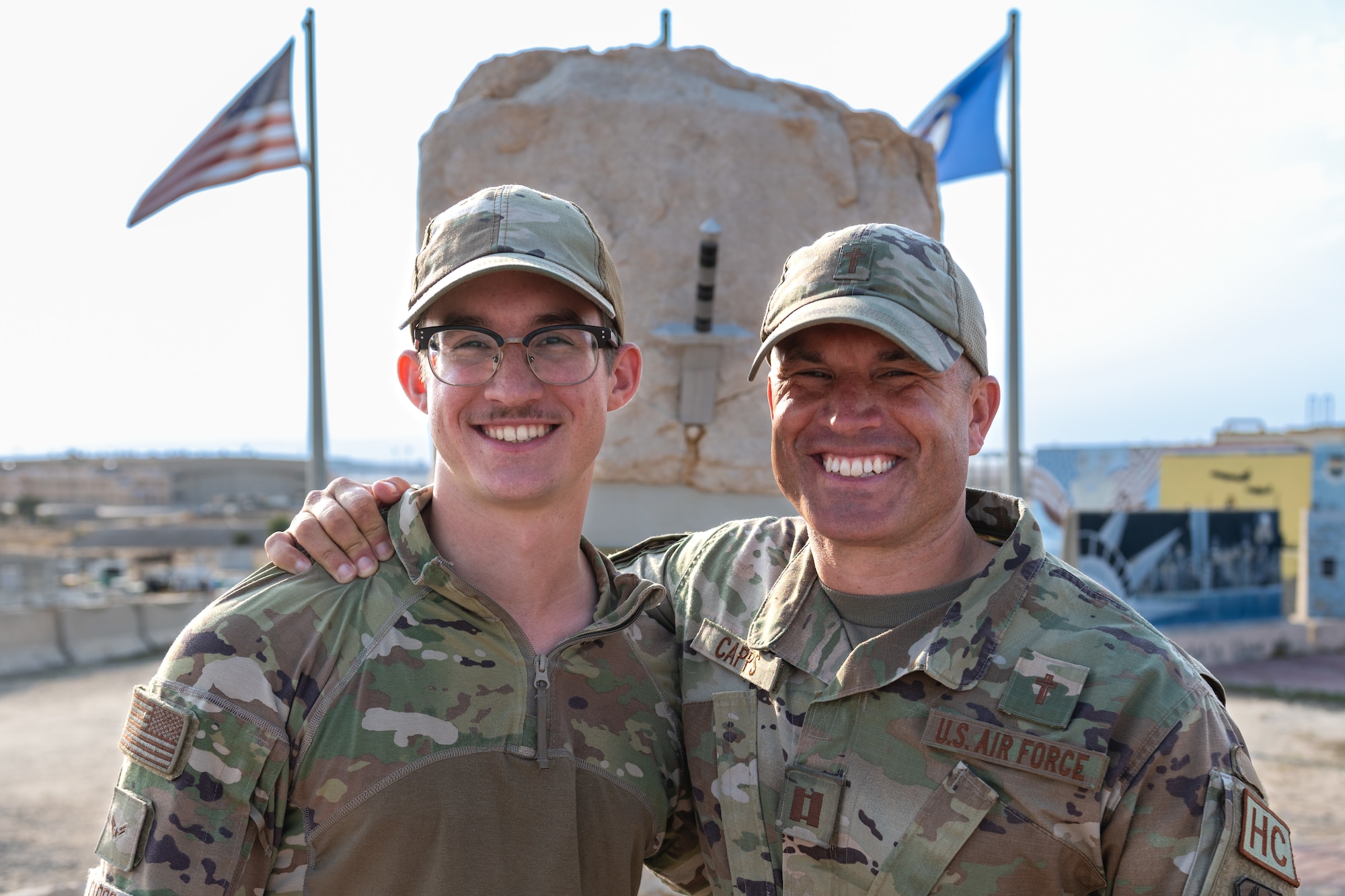 two men stand together in front of rock