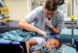Ensign Jenna Bumiller listens to respirations on a Palauan pediatric patient aboard USNS Mercy (T-AH 19) in Koror, Palau, during Pacific Partnership 2024.