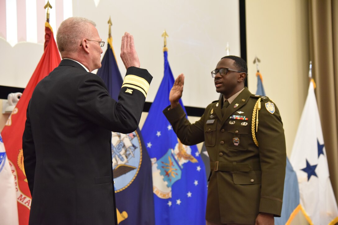 Photo is of two men in military uniform holding up their right hand as the oath of office is administered.