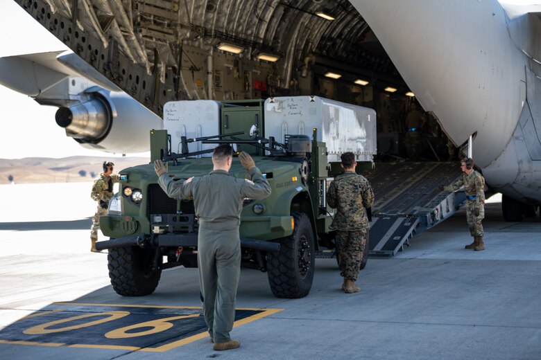 U.S. Airmen and Marines work to secure a Navy/Marine Corps Expeditionary Ship Interdiction System (NMESIS) Launcher onto a C-17 Globemaster III