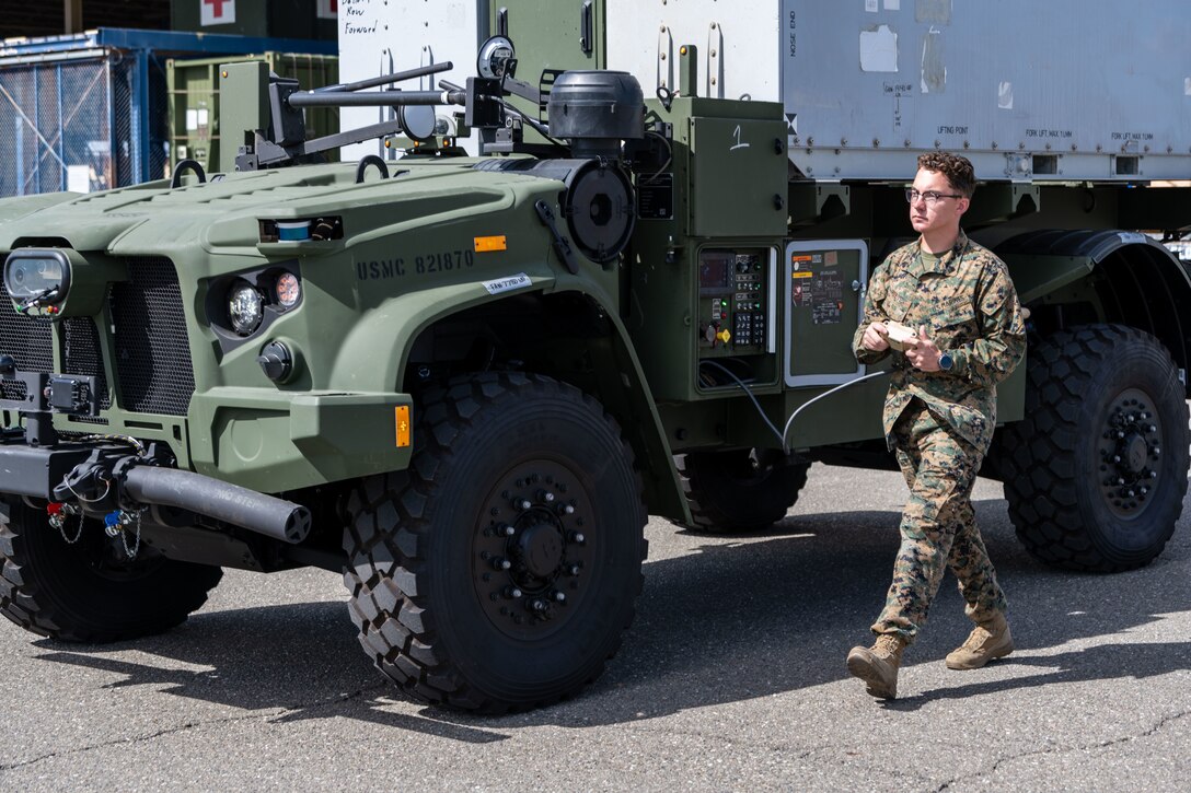 U.S. Marines from the Program Manager Long Range Fires (PM LRF) New Equipment Training Team (NETT), walk two Navy/Marine Corps Expeditionary Ship Interdiction System (NMESIS) Launchers towards a C-17 Globemaster III loading area at Travis Air Force Base, California, Sept. 25, 2023.