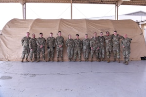 A group of people pose in front of a tent.