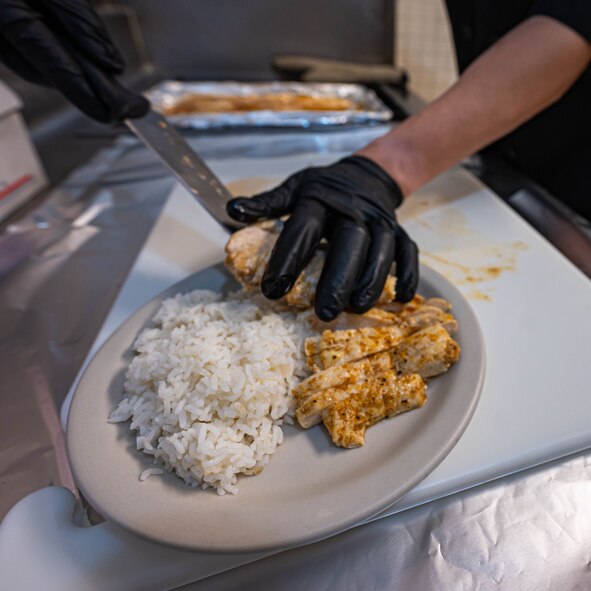 Chicken gets plated for a customer at Missile Alert Facility Oscar, North Dakota, Dec. 21, 2023. A missile chefs’ duties at a MAF include completing and stocking inventory as well as preparing, cooking and cleaning after each mealtime. (U.S. Air Force photo by Senior Airmen Alexander Nottingham)