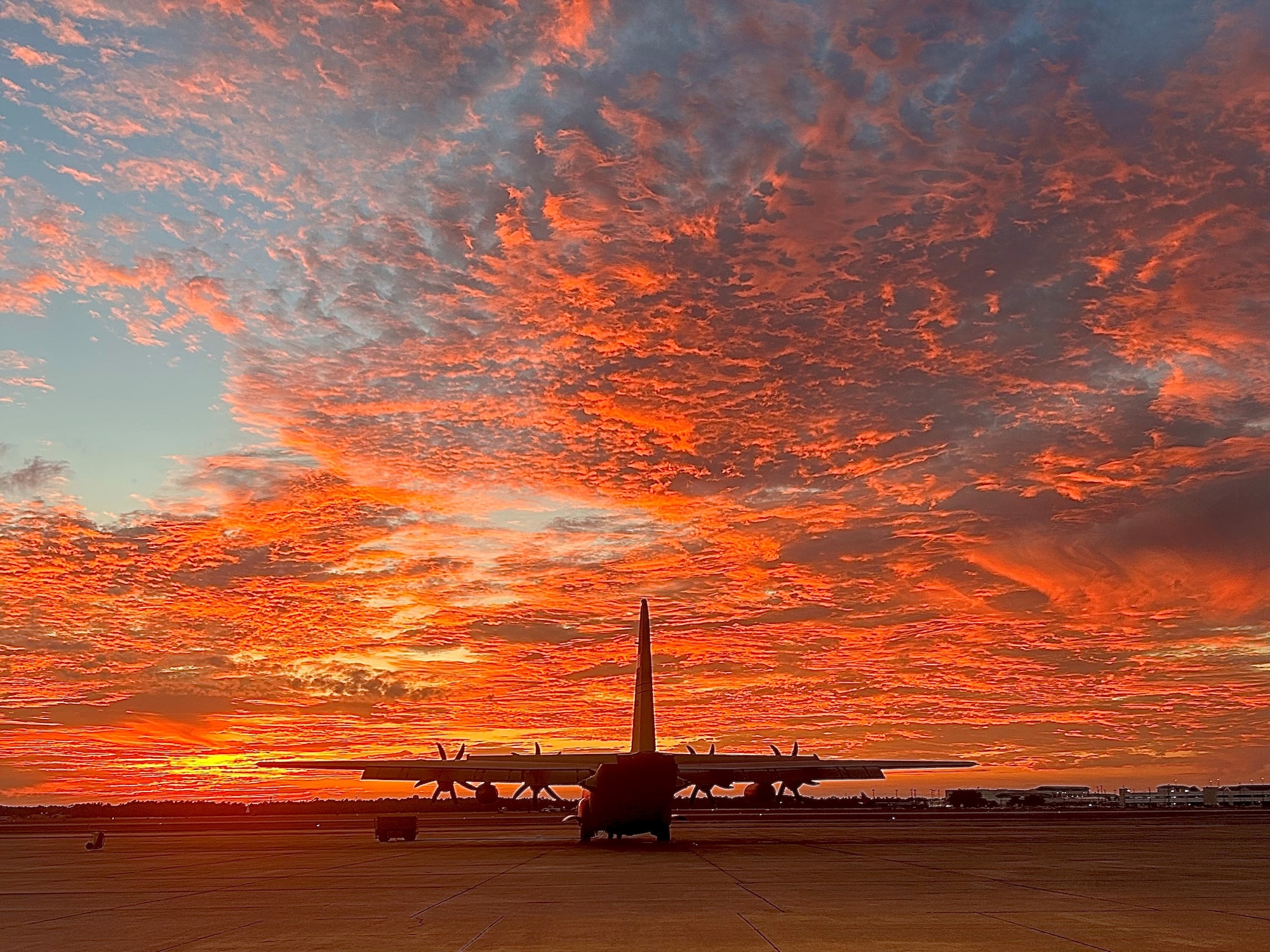 a C-130 is parked on a flightline during sunset