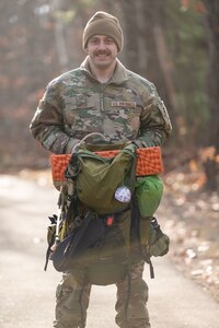 An Airman holds his hiking backpack in the woods.
