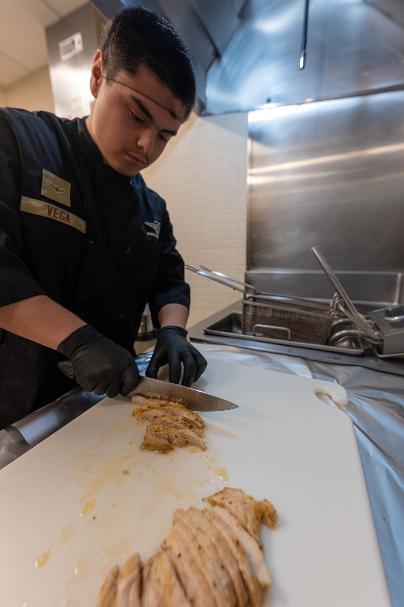 Airman 1st Class Oscar Vega, 5th Force Support Squadron food service specialist, cuts chicken at Missile Alert Facility Oscar, North Dakota, Dec. 21, 2023. During their deployment, missile chefs can make 20 to 40 meals a day for the Airmen stationed on site. (U.S. Air Force photo by Senior Airmen Alexander Nottingham)