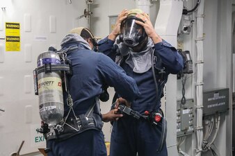 Sailors aboard USS Thomas Hudner (DDG 116) don firefighting equipment during a damage control drill.