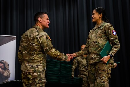 Sergeant Major of the Army shakes hands with a female Soldier who has graduated the Army Recruiting and Retention College Course