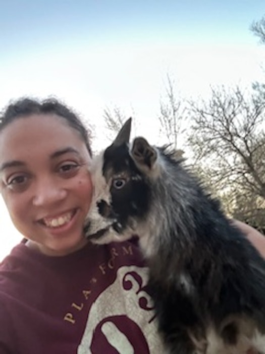 Image of Master. Sgt. Angelique Brooks outside holding a tiny goat.