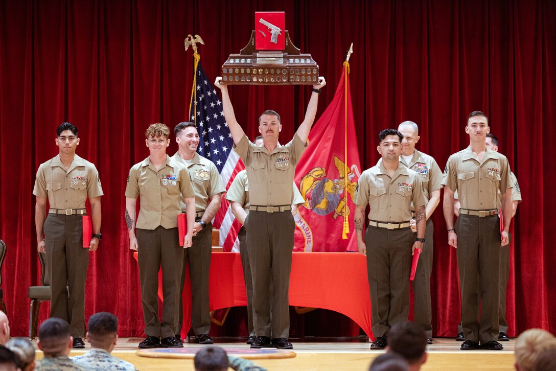 U.S. Marines with the 9th Engineer Support Battalion, 3rd Marine Logistics Group, hold up the Pistol Team Trophy during Marine Corps Marksmanship Competition Far East Awards Ceremony on Camp Hansen, Okinawa, Japan, Dec. 15, 2023. The Pistol Team Trophy is awarded to the highest scoring pistol team at MCMC-Far East. MCMC-Far East is an annual two-week event held to improve Marines’ marksmanship, combat readiness, and weapon proficiency. Marines utilize the first week to learn various techniques and fundamentals from members of the Marine Corps Shooting Team and compete the following week as individuals and teams. (U.S. Marine Corps photo by Cpl. Vincent Pham)