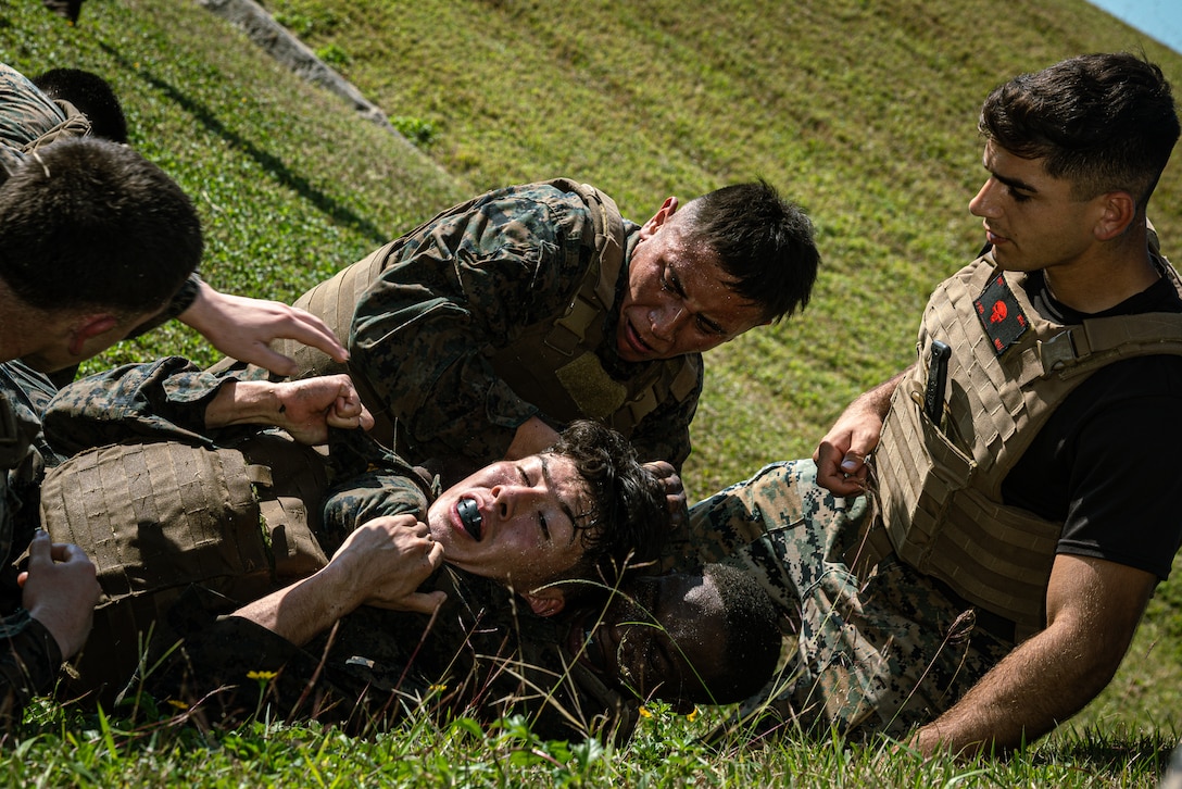 U.S Marines with 3rd Marine Division, III Marine Expeditionary Force Information Group, and 3rd Marine Logistics Group, grapple during the culminating event of a Martial Arts Instructor Course on Camp Hansen, Okinawa, Japan, Dec. 14, 2023. The MAI course is a three-week course that implements physical training and academic instruction for instructor trainees. The demanding physical intensity prepares trainees to perform Marine Corps Martial Arts Program techniques through the different elements of war. Coursework evaluations ensure that all newly graduated instructors have more than enough knowledge to carefully supervise and instruct Marines who are looking to make MCMAP belt advancements. (U.S. Marine Corps photo by Cpl. Thomas Sheng)