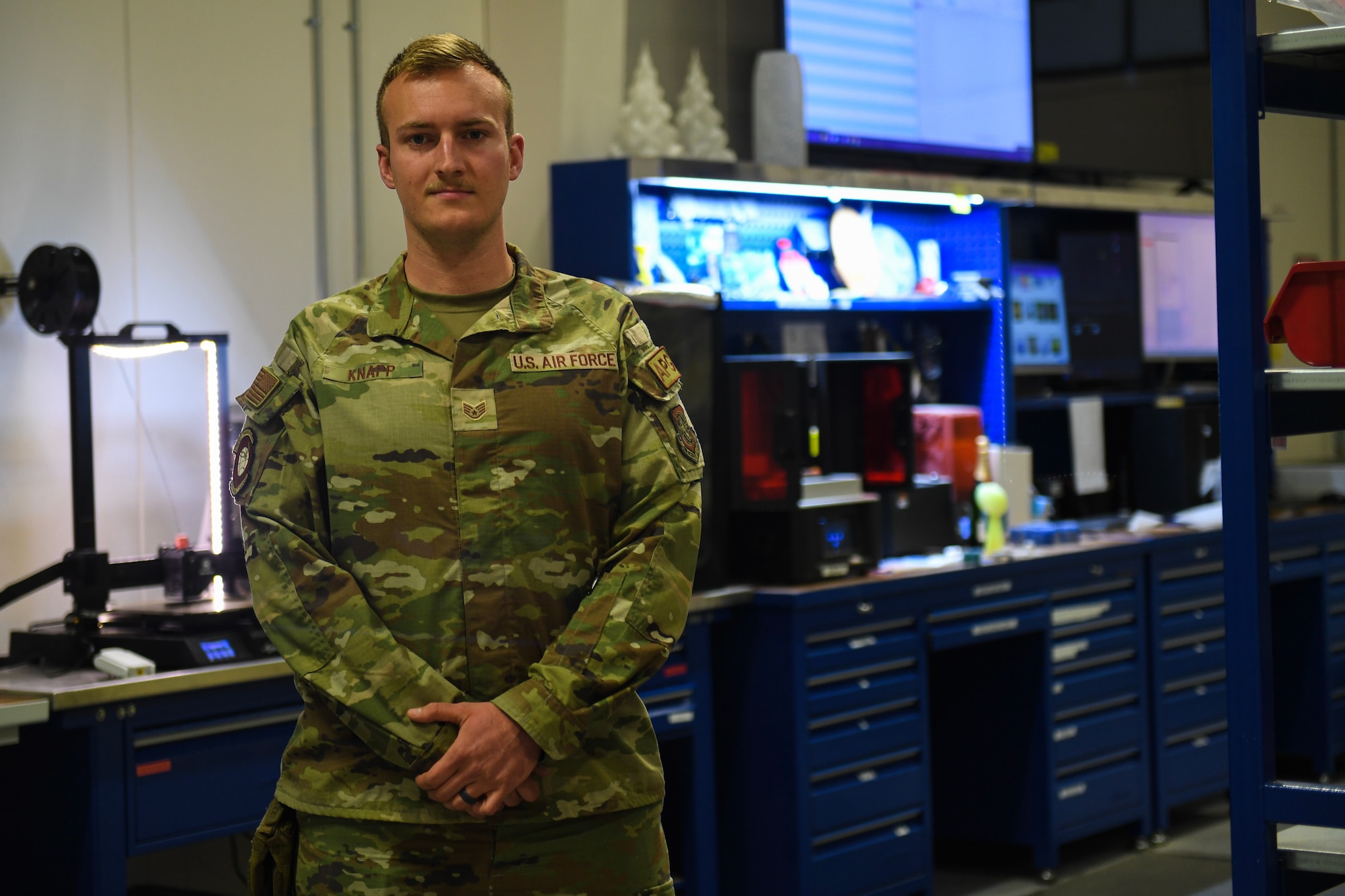 Air Force NCO stands in front of fabrication equipment