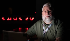 A man sitting in a dark room in front of a laptop.