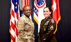 Two female Soldiers pose together in front of an array of flags