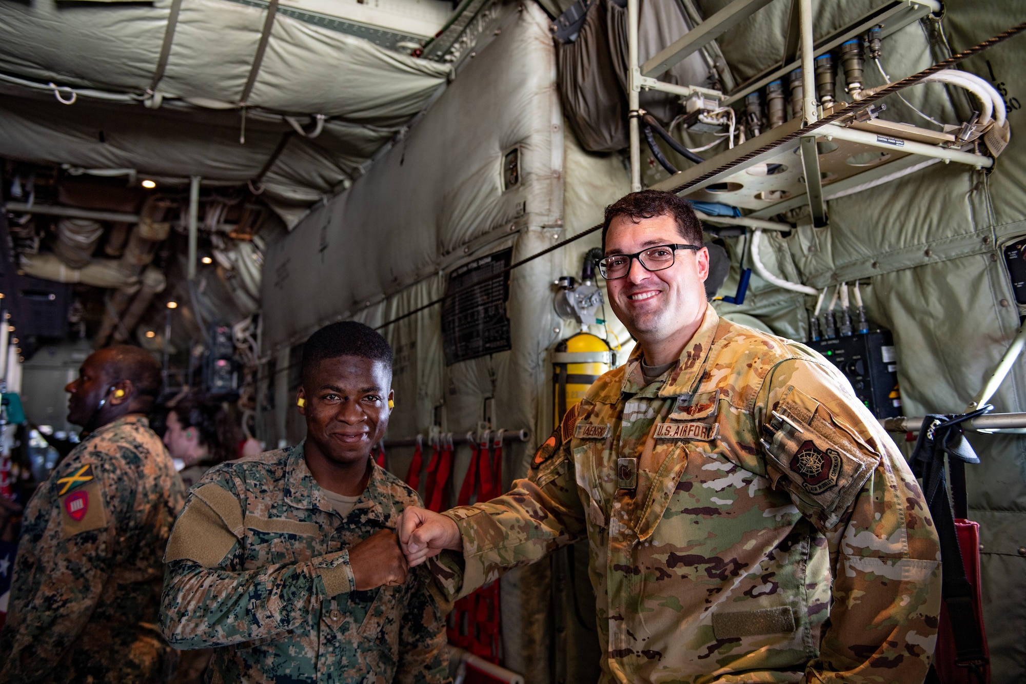 A U.S. Air Force loadmaster, right, and a Jamaican Defense Force member smile for a photo inside a C-130J Super Hercules at the Norman Manley International Airport near Kingston Jamaica, Feb. 28, 2023. U.S., Jamaican and Canadian forces came together to ensure when disaster strikes, they will be able to integrate forces and work together to provide life-saving aid and support throughout the Caribbean. (U.S. Air Force photo by Airman 1st Class Courtney Sebastianelli)
