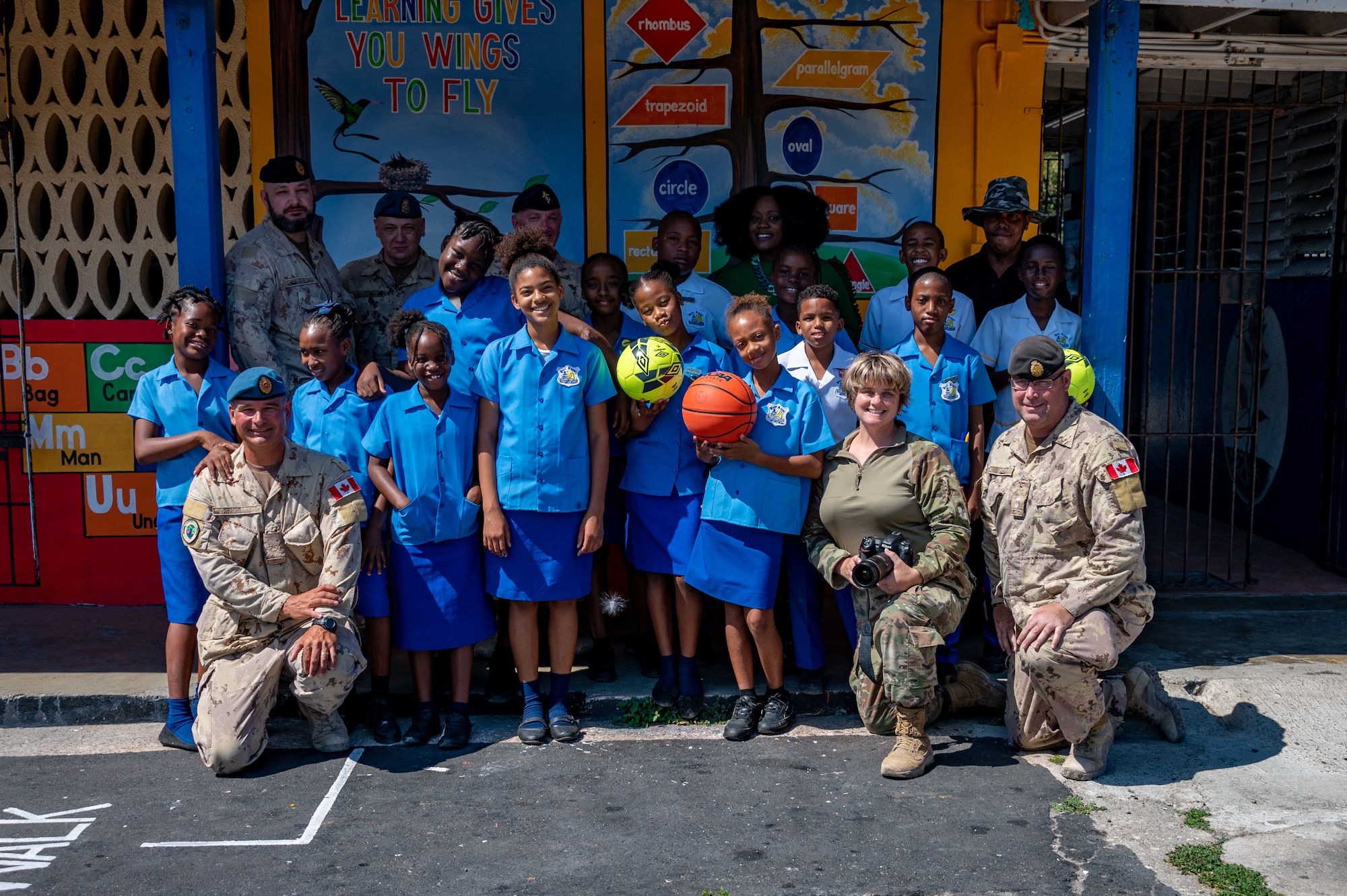 U.S. Air Force and Canadian Armed Forces smile for a photo at the Port Royal Primary and Infant School in Port Royal Jamaica, Feb. 27, 2023. During Operation Forward Tiger, an Airman from the 23rd Air Expeditionary Wing teamed with Canadian Armed Forces to visit the children who attend the school to donate recreational equipment and discuss the importance of education and values. (U.S. Air Force photo by Airman 1st Class Courtney Sebastianelli)