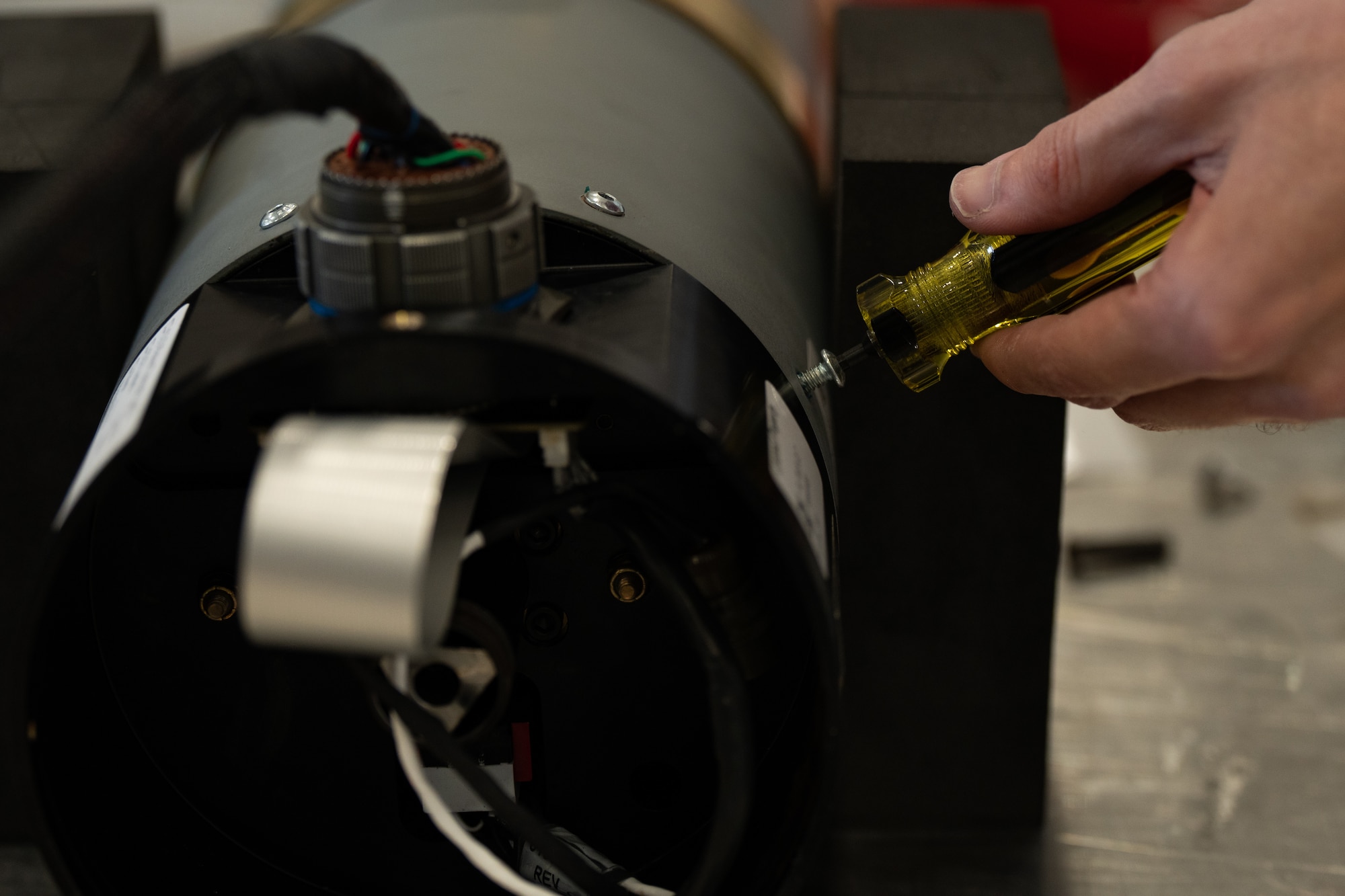 A civilian contractor tightens the screws of a common launch tube, fastening the Altius 600 Group 2 small uncrewed aircraft system in place for an Adaptive Airborne Enterprise (A2E) demonstration at Cannon Air Force Base, N.M., Nov. 28, 2023. Adaptive Airborne Enterprise will utilize large and small UAS at scale, including a mix of attritable and expendable systems with modular payloads. (U.S. Air Force photo by Staff Sgt. Nicholas Swift)