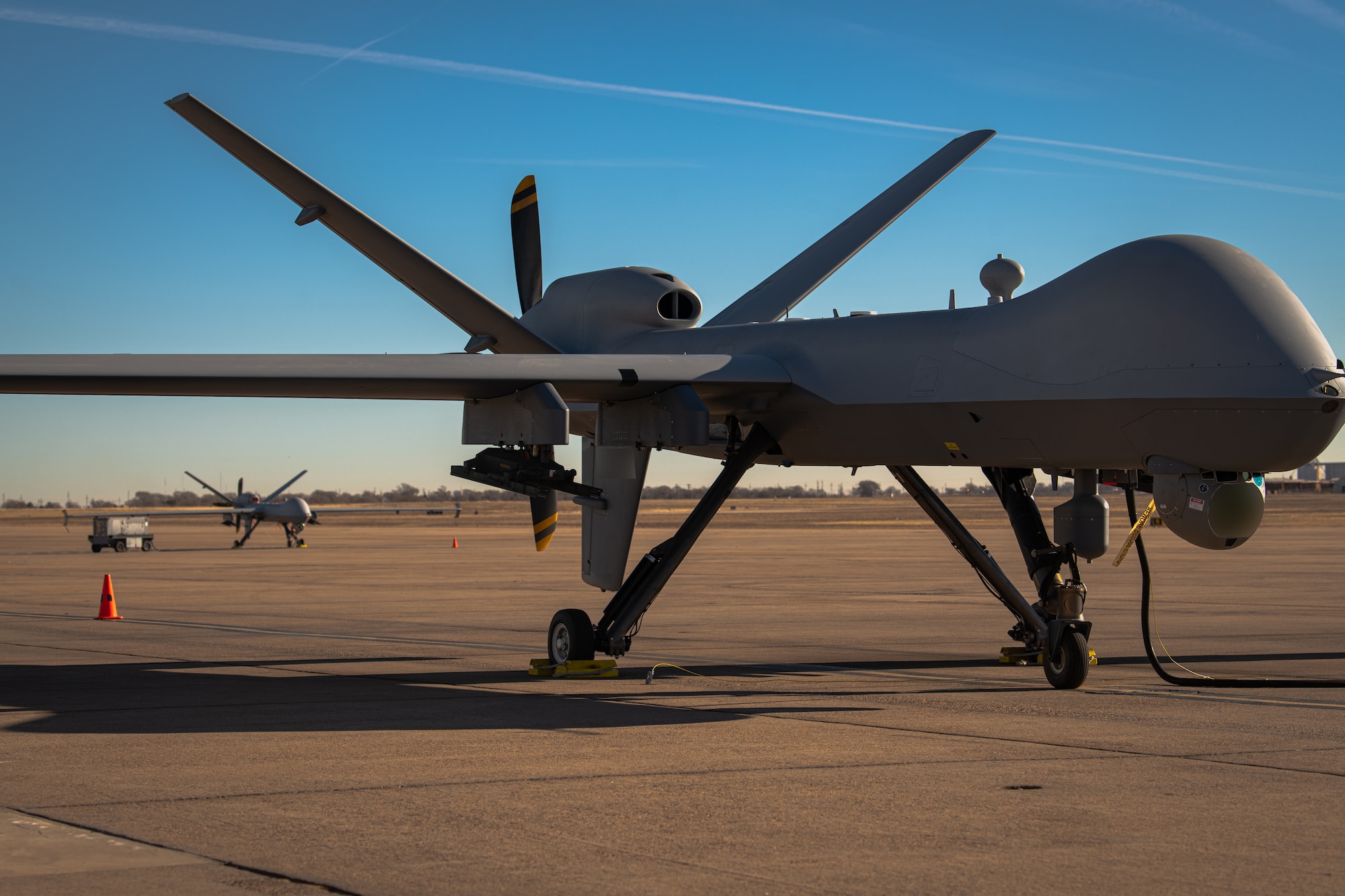 Two MQ-9A Reaper remotely piloted aircraft operated by the 3rd Special Operations Squadron undergo pre-flight checks before an experimental multi-aircraft control flight for the Adaptive Airborne Enterprise (A2E) at Cannon Air Force Base, N.M., Dec. 6, 2023. MQ-9 units will leverage multiple platforms and later incorporate autonomy to deliver capabilities to special operations forces and the joint force across the spectrum of operations (U.S. Air Force photo by Staff Sgt. Vernon R. Walter III) (This photo has been edited for security purposes by blurring out aircraft information)