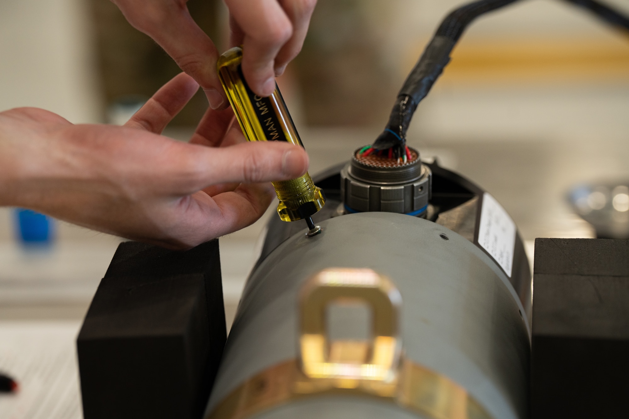 A civilian contractor tightens the screws of a common launch tube, fastening the Altius 600 Group 2 small uncrewed aircraft system in place for an Adaptive Airborne Enterprise (A2E) equipment demonstration at Cannon Air Force Base, N.M., Nov. 28, 2023. A2E will simplify command and control complexity, cost and training using a common control interface, resulting in reduced personnel requirements and the ability for remotely piloted aircraft operators to control air assets without being fixed to an operating location. (U.S. Air Force photo by Staff Sgt. Nicholas Swift)