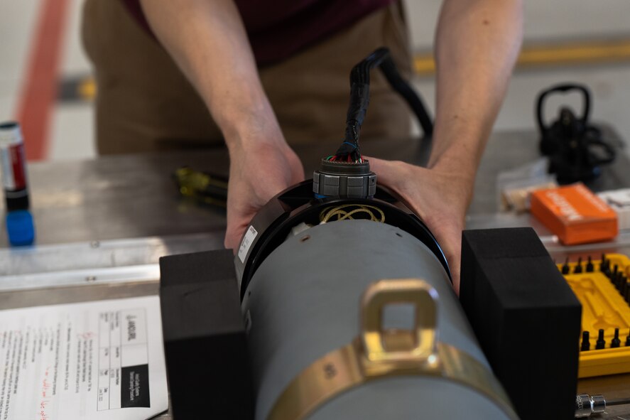 A civilian contractor installs the Altius 600 Group 2 small uncrewed aircraft system into a common launch tube in preparation for an Adaptive Airborne Enterprise (A2E) demonstration at Cannon Air Force Base, N.M., Nov. 28, 2023. Adaptive Airborne Enterprise marks the evolution from exclusively using the MQ-9 platform for Intelligence, Surveillance and Reconnaissance and strike capabilities. MQ-9 units will leverage multiple platforms, and later incorporate autonomy, to deliver capabilities to special operations forces and the joint force across the spectrum of operations. Air Force Special Operations Command expects to increase the number of platforms its operators can manage by an order of magnitude and, through those systems, the area of the battlespace they affect. (U.S. Air Force photo by Staff Sgt. Nicholas Swift)