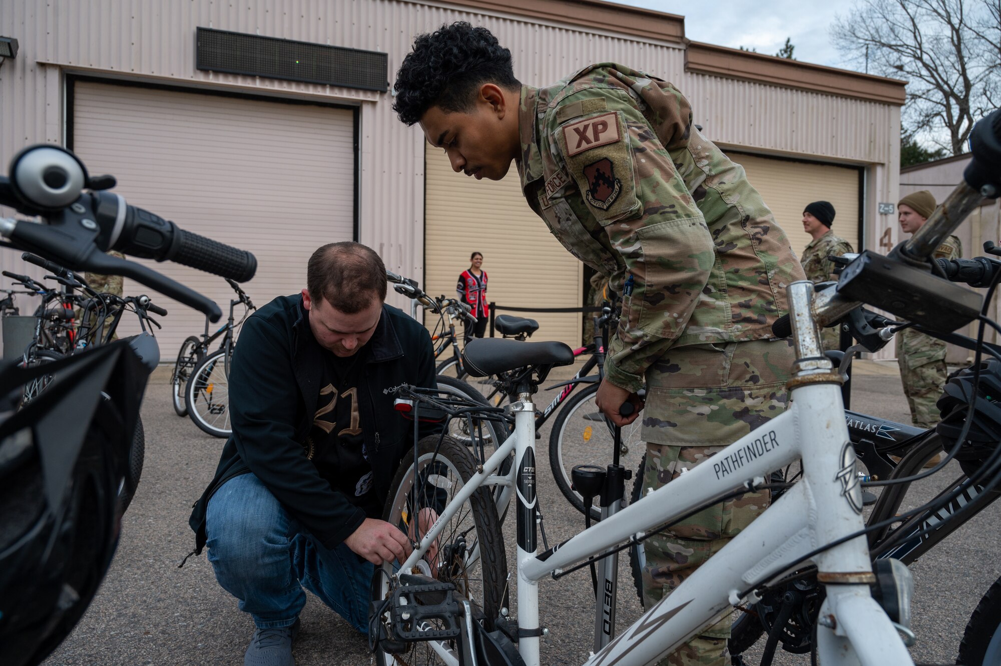 Kristian Hoffman-Martine and Joseph Berggren pump air into a bicycle tire during a bike exchange at Kunsan AB.