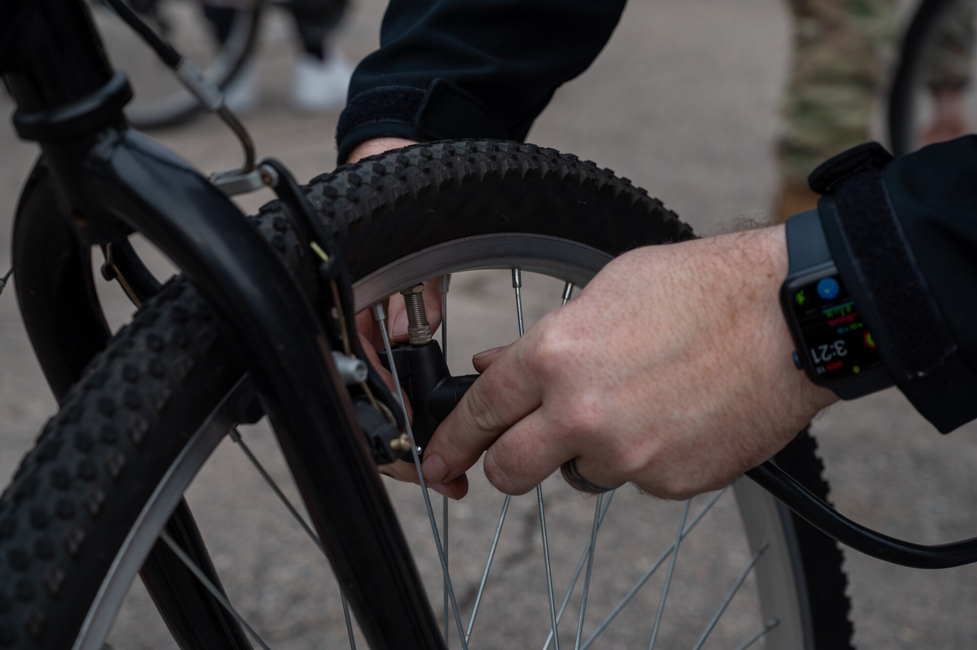 Joseph Berggren attaches an air pump nozzle to a bicycle tire during a bike exchange.