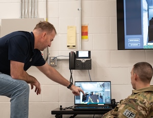 James Wende, Air Force Business Development, Street Smarts VR, left shows U.S. Air Force Tech. Sgt. Marshal Freeman, right, 133rd Security Forces Squadron, the capabilities of the virtual reality training system in St. Paul, Minn., Dec. 20, 2023.