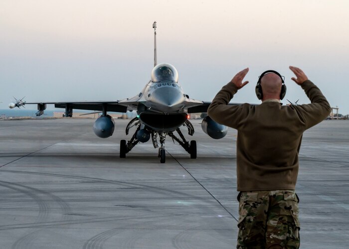 Tech. Sgt. John Raebig, an F-16 crew chief, marshals a U.S. F-16 Fighting Falcon to a parking space at an undisclosed location in the U.S. Central Command area of responsibility, Jan. 6, 2024.