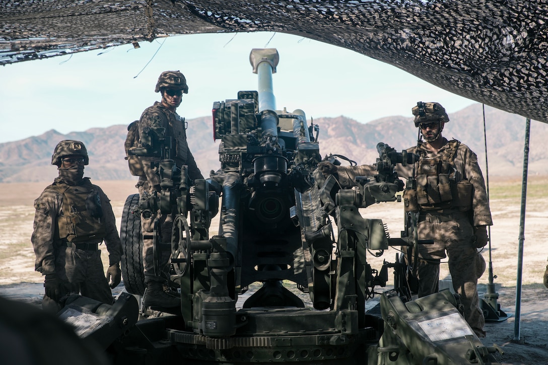 U.S. Marine Corps field artillery cannoneers assigned to Charlie Battery, Battalion Landing Team 1/5, 15th Marine Expeditionary Unit, stand in front of an M777 towed 155 mm howitzer between fire missions during an expeditionary fires exercise at Marine Corps Base Camp Pendleton, California, Dec. 10, 2023. During the exercise, the 15th MEU was embarked aboard the Boxer Amphibious Ready Group in the Pacific Ocean coordinating integrated fires with aviation and indirect fires assets ashore.