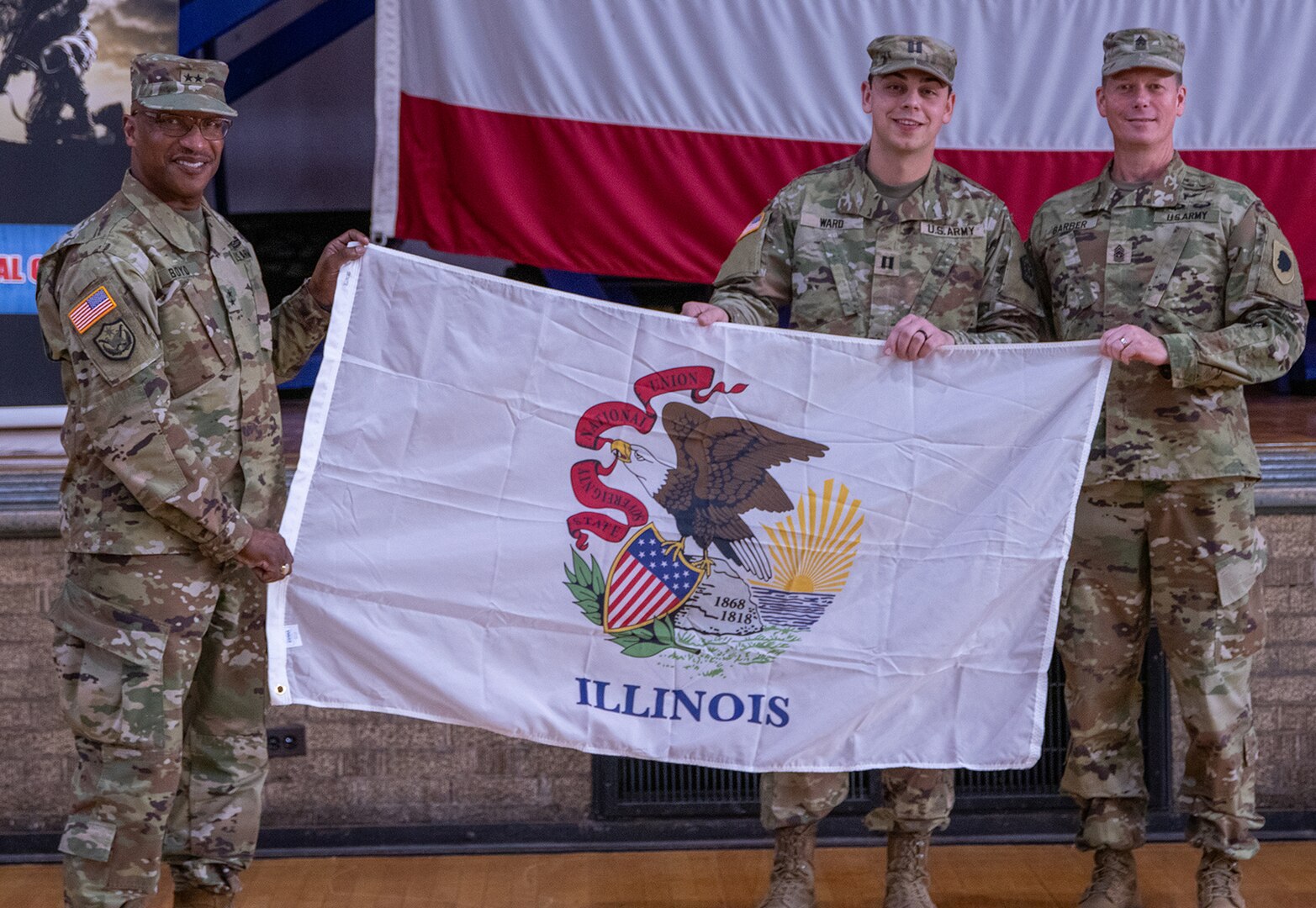 Maj. Gen. Rodney Boyd, Assistant Adjutant General – Army, and Commander of the Illinois Army National Guard, left, and Command Sgt. Maj. Phillip Barber, State Command Sergeant Major, right, present the state of Illinois flag to Capt. Cameron Ward, Commander, 1863rd Finance Management Support Detachment during a mobilization ceremony at the Northwest Armory in Chicago Jan. 5.