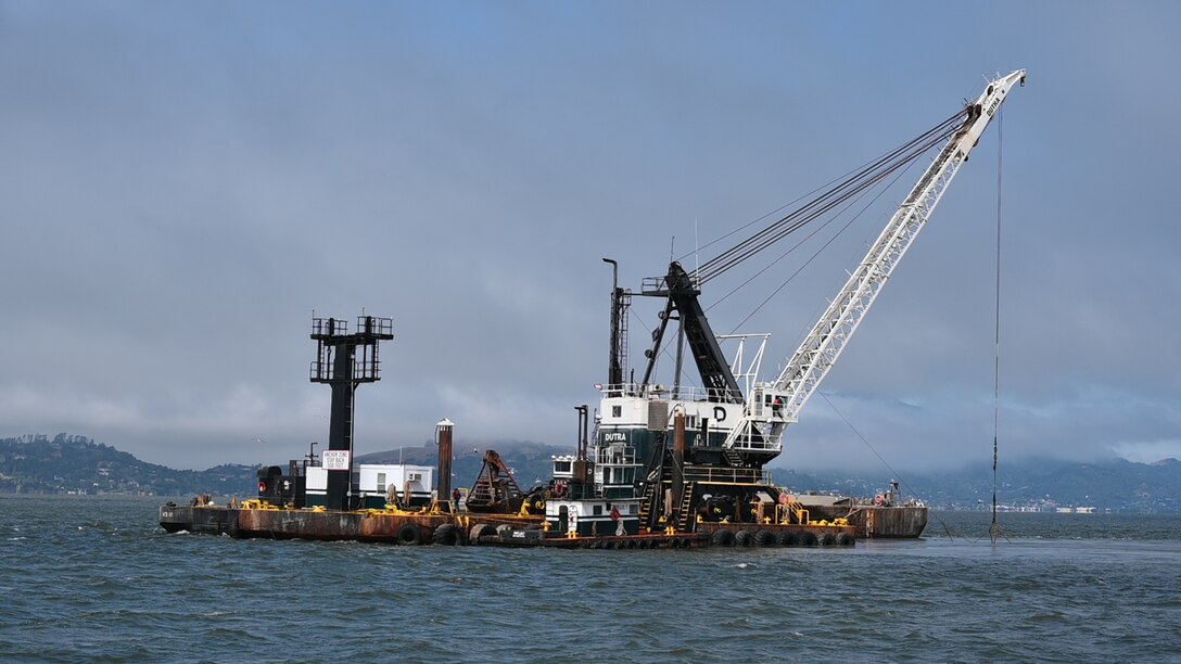 a lonely dredge out on the blue water with dark clouds behind it.