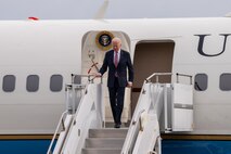 A photo of President Biden walking down stairs from an aircraft.