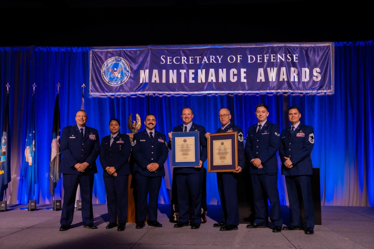 A group of people pose for a photo holding awards.