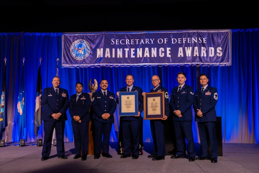 A group of people pose for a photo holding awards.