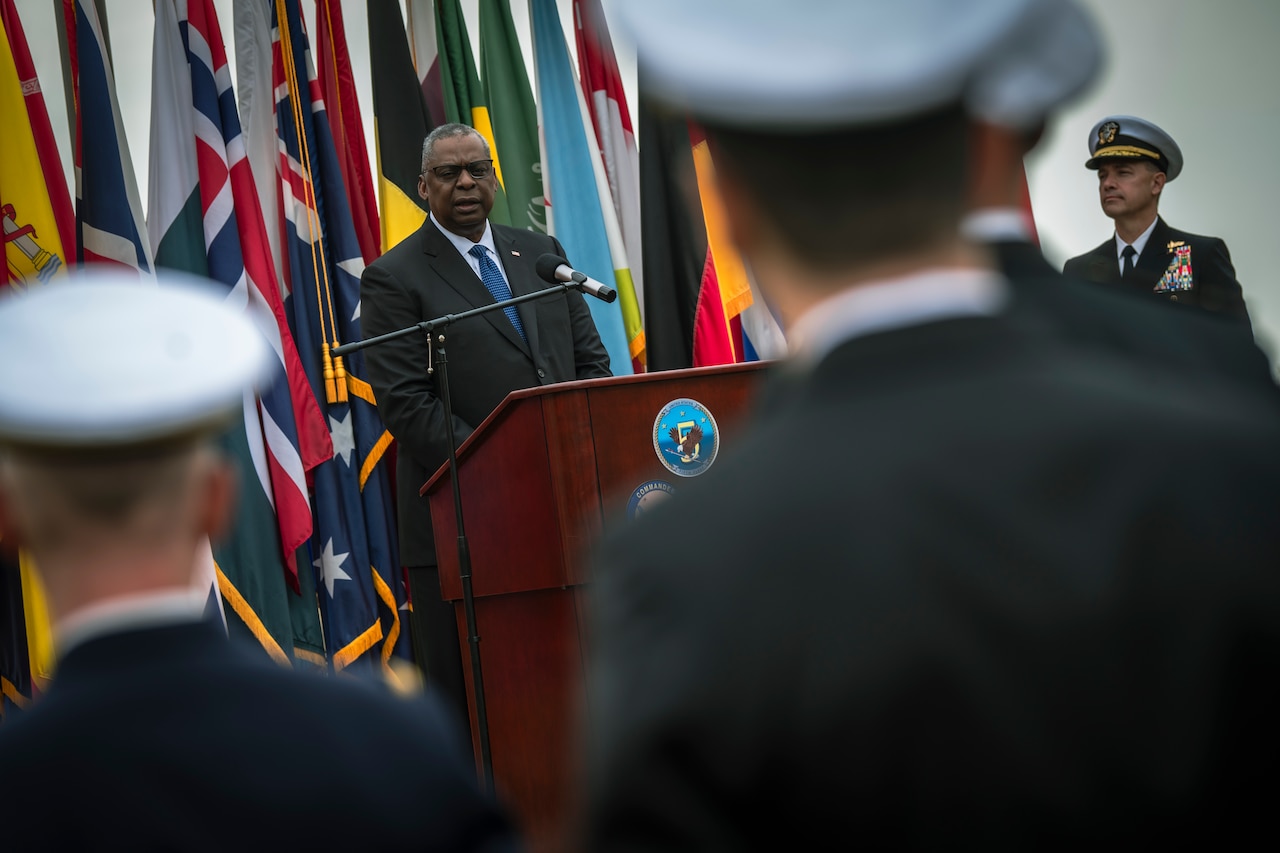A man addresses service members in uniform from a lectern.