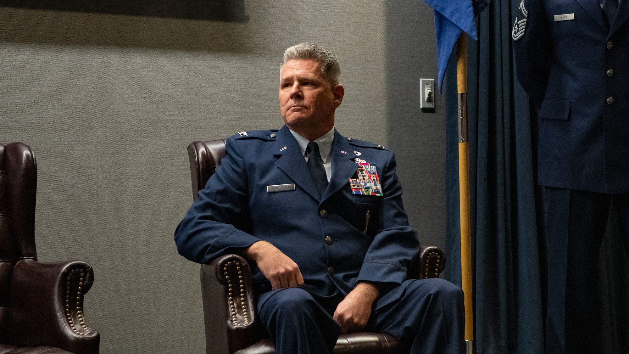 A man in Air Force service dress sits in a brown chair.
