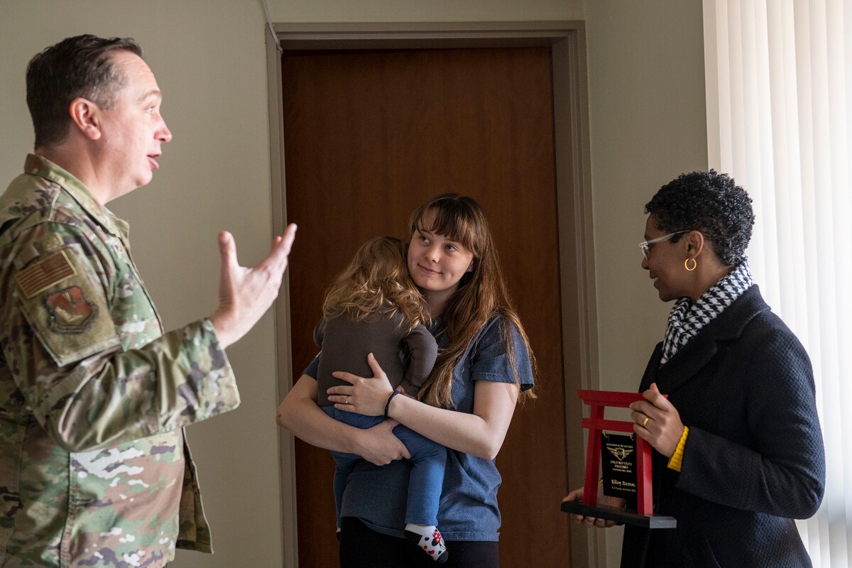 An Airman and a Director congratulate an award winner at their home