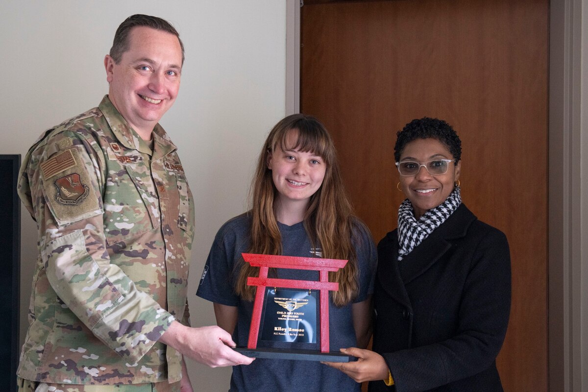 Airmen and people stand together for a group photo with an award presentation
