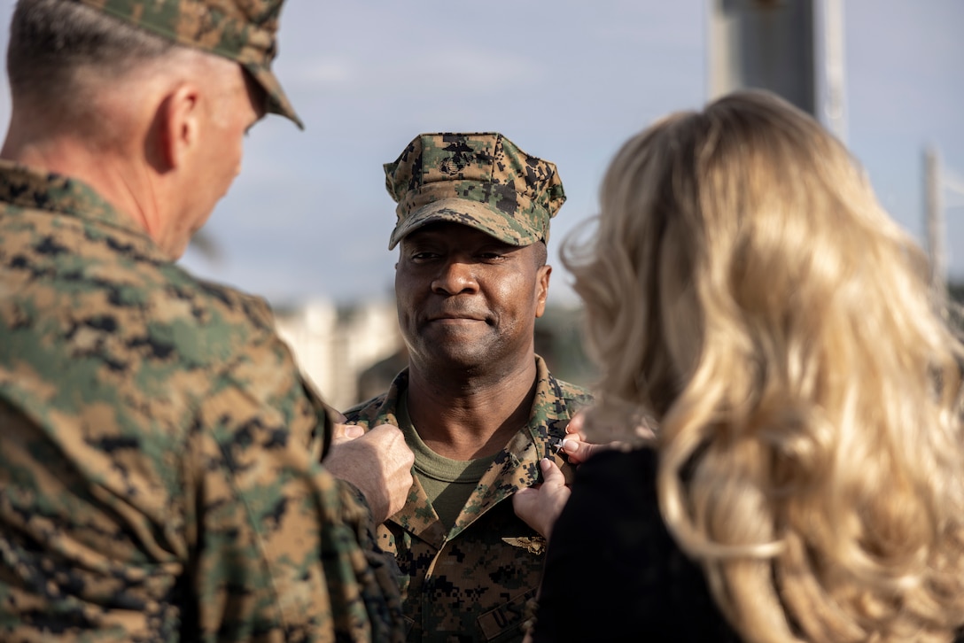 U.S. Marine Corps Col. Kelvin Gallman, the 1st Marine Aircraft Wing assistant wing commander, is frocked to the rank of brigadier general by his wife, Janna Gallman, and Maj. Gen. Eric Austin, the 1st Marine Aircraft Wing commanding general, on Camp Foster, Okinawa, Japan, Jan. 8, 2024. Frocking is a tradition where Marines are advanced to the next pay grade, assuming the title and the responsibilities prior to their official date of promotion. (U.S. Marine Corps photo by Lance Cpl. Sav Ford)