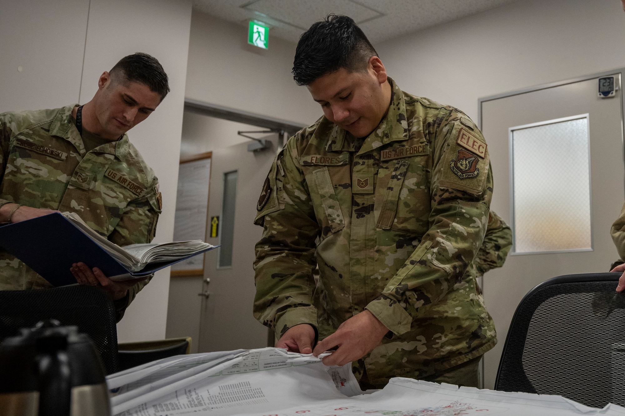 U.S. Air Force Technical Sgt. Enrique Flores, Non-Commissioned Officer in Charge of the 35th Civil Engineering Squadron electrical systems flight, demonstrates the trouble shooting process with maps during a Wild Weasel Walk-through at Misawa Air Base, Japan.