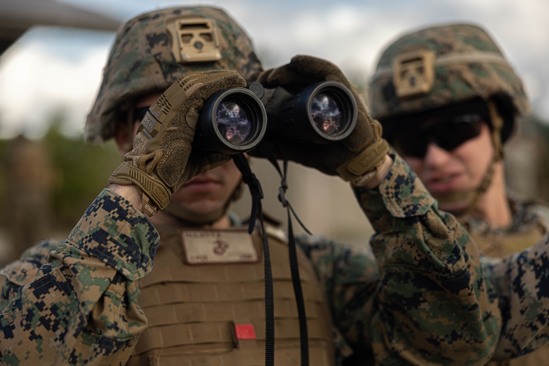 U.S. Marine Corps Cpl. Ryan Paulsen, left, and Cpl. Robert Boesch, right, both generator mechanics with 3rd Maintenance Battalion, 3rd Marine Logistics Group, identify range targets with binoculars at Camp Hansen, Okinawa, Japan, Dec. 22, 2023. The reason for the training was to increase their lethality, survivability, and capability when it comes to employing the M2 .50 Caliber machine gun in a mounted platform. (U.S. Marine Corps photo by Lance Cpl. Weston Brown)