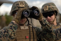 U.S. Marine Corps Cpl. Ryan Paulsen, left, and Cpl. Robert Boesch, right, both generator mechanics with 3rd Maintenance Battalion, 3rd Marine Logistics Group, identify range targets with binoculars at Camp Hansen, Okinawa, Japan, Dec. 22, 2023. The reason for the training was to increase their lethality, survivability, and capability when it comes to employing the M2 .50 Caliber machine gun in a mounted platform. (U.S. Marine Corps photo by Lance Cpl. Weston Brown)