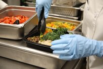 Pfc. Erica Kenmegne, a 92G culinary specialist with 2nd Battalion, 87th Infantry Regiment, 2nd Brigade Combat Team, 10th Mountain Division (LI), adds the final touch to a Meal Prep to-go meal at the Commando Warrior Restaurant at Fort Drum. The Meal Prep program is designed to offer Soldiers healthy to-go options. (U.S. Army photo by Capt. Jessica George)