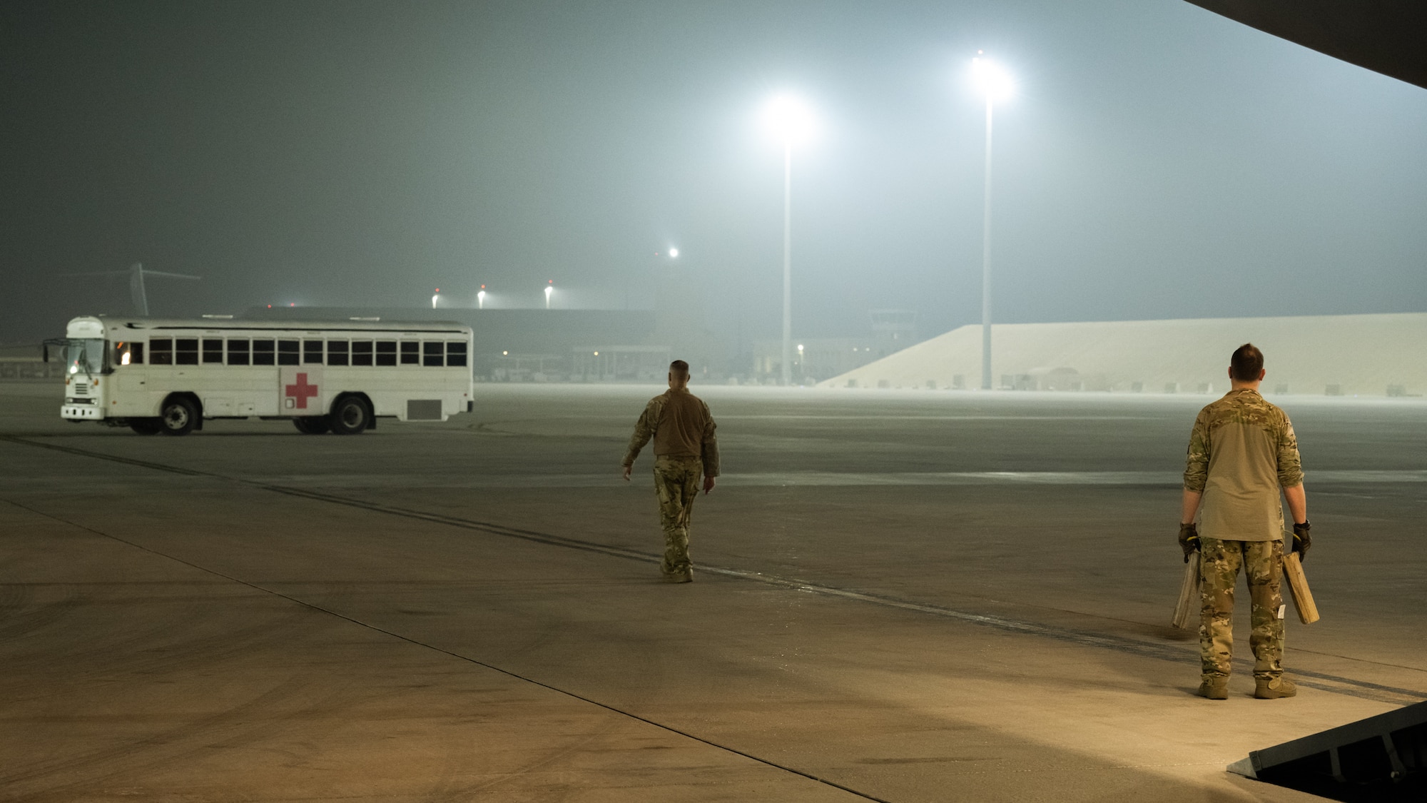 Two Airmen from the 105th Airlift Wing prepare to guide a medical bus towards the back of a C-17 Globemaster III.